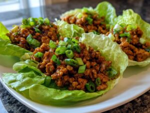 Four fresh chicken lettuce wraps filled with savory ground chicken mixture and topped with green onions.