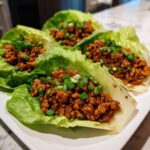 Four servings of savory chicken lettuce wraps filled with ground chicken mixture and topped with green onions.