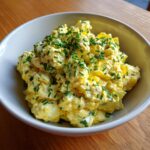 A creamy bowl of amazing egg salad generously topped with freshly chopped green chives.