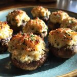 Close-up of several baked stuffed mushrooms with golden, cheesy tops garnished with parsley.
