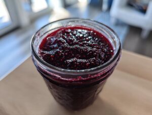 Close-up of rich, dark blackberry jam filling a canning jar, showing visible seeds and texture.