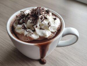 A close-up of a rich, dark boozy hot chocolate topped with whipped cream and chocolate shavings.