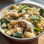 Close-up of a creamy chicken caesar pasta salad featuring rotini pasta, shredded chicken, and green lettuce.
