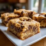 A close-up of a thick, chewy chocolate chip cake mix cookie bars square on a white plate.