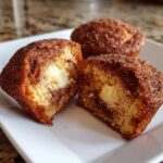 Close-up of a cinnamon cream cheese muffin cut in half, revealing the creamy center.