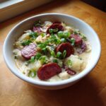 A hearty bowl of creamy Cajun potato soup topped with sliced andouille sausage and green onions.