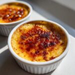 Close-up of a classic Creme Brulee with a deeply caramelized, crackling sugar top in a white ramekin.