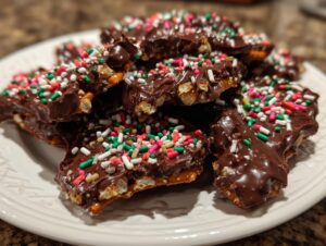 Close-up of broken pieces of Crockpot Christmas Crack, covered in melted chocolate and festive holiday sprinkles.