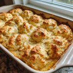 Close-up of an easy chicken cobbler with golden brown biscuits bubbling over a creamy filling in a ceramic baking dish.