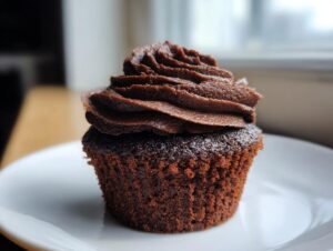 A close-up of one moist, dark chocolate cupcake topped with perfectly piped chocolate frosting, ready to eat.