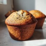 Close-up of a perfectly baked banana nut muffin with a golden-brown top, showing specks of nuts or banana.