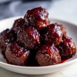 A tempting pile of glistening Grape Jelly Meatballs coated in a thick, dark, sweet and savory glaze.