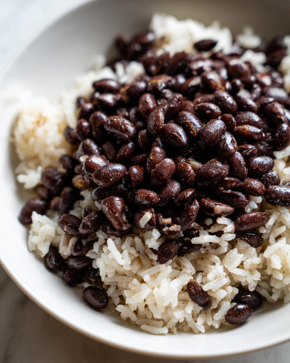A close-up, top-down view of a simple serving of black beans and white rice, highlighting the texture of the beans and rice for a healthy beans and rice recipe.