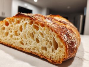 Close-up of the interior crumb structure of a freshly baked Italian bread loaf, showing large, airy holes.