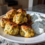 A plate of golden brown greek chicken meatballs served alongside a dollop of creamy tzatziki sauce.