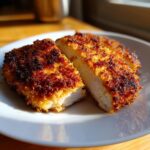 Cross-section of juicy parmesan crusted chicken showing the golden-brown crust and white interior.