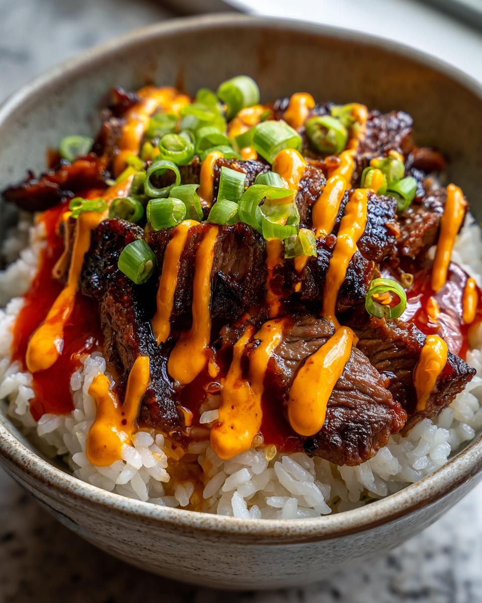 Close-up of delicious Korean BBQ steak rice bowls topped with spicy orange sauce and sliced green onions.