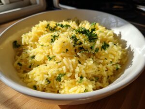 A close-up of fluffy, yellow Mediterranean rice garnished with fresh chopped parsley in a white bowl.