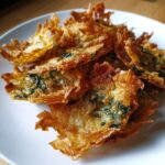 A pile of golden brown, crispy Mediterranean Spinach and Feta Cheese Crisps served on a white plate.
