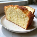 Close-up of a thick slice of moist million dollar pound cake showing its fine, yellow crumb and golden-brown crust.