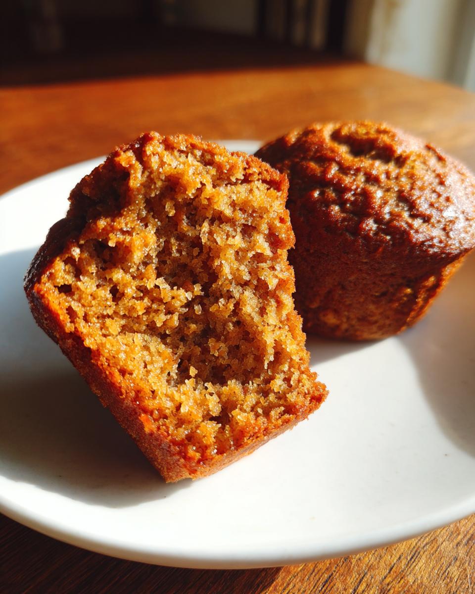 Close-up of a honey bran muffin cut in half showing its moist, textured interior next to a whole muffin.