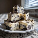 A stack of creamy white Oreo fudge squares loaded with dark chocolate cookie pieces, ready to eat.