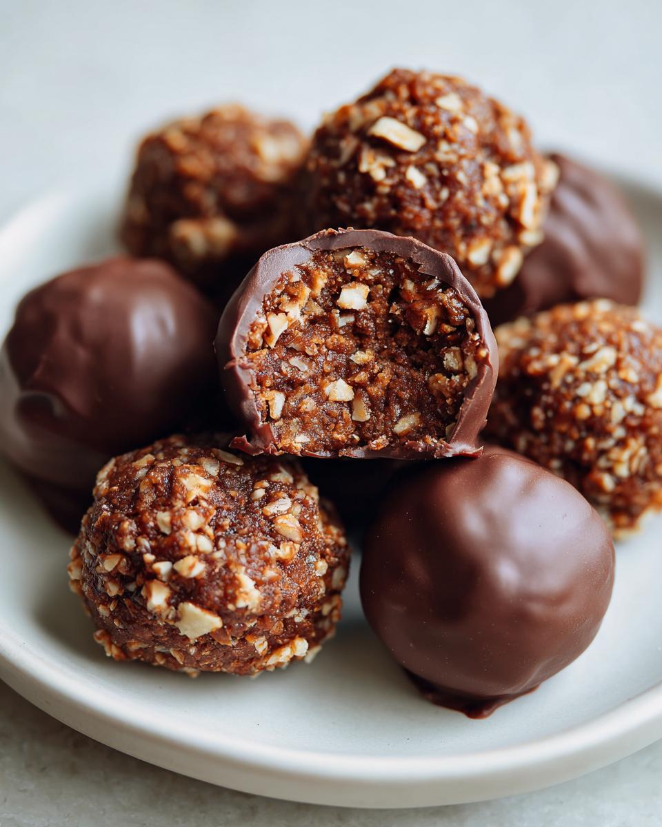 A close-up of several pecan pie balls, some coated in chocolate and others rolled in chopped nuts.