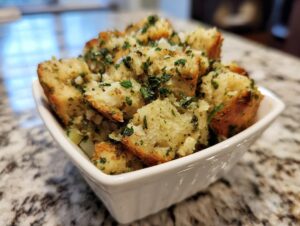 Close-up of fluffy bread cubes in a white bowl, featuring savory herbs, ready to eat crock pot stuffing.