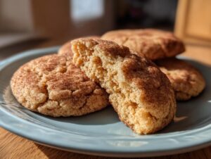 Close-up of a soft, chewy Snickerdoodle cookie broken in half showing the texture, dusted with cinnamon sugar.
