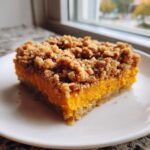 A square slice of rich orange southern sweet potato casserole topped with a thick, crunchy pecan crumble.