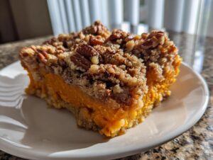A close-up of a rich, orange slice of southern sweet potato casserole topped with a crunchy pecan streusel.