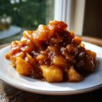 A mound of glossy, spiced apple pie filling recipe chunks served on a white plate.