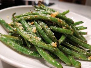 Close-up of bright green beans roasted and topped with grated Parmesan cheese and seasoning.