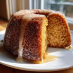A slice cut from a moist Bacardi Rum Cake, drizzled generously with a light brown rum glaze.