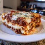 A generous slice of homemade lasagna showing rich meat sauce, creamy ricotta, and melted cheese topping.