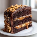 A decadent slice of chocolate caramel toffee crunch cake showing rich layers of dark cake, caramel filling, and crunchy toffee topping.