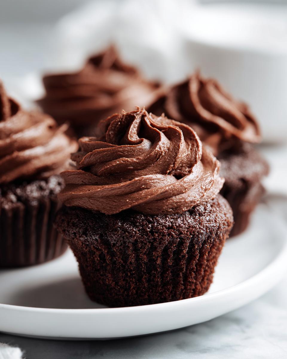 Close-up of a chocolate cupcake topped with perfectly piped, rich chocolate frosting.