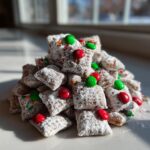 A mound of powdered sugar-coated christmas puppy chow mixed with red and green M&Ms.