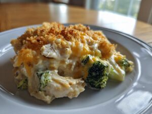A close-up serving of creamy Chicken Divan featuring shredded chicken, bright green broccoli florets, and a golden, crunchy topping.