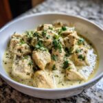 Close-up of creamy coconut lime chicken pieces in a white bowl, topped with fresh cilantro.