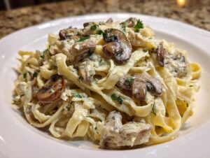 Close-up of creamy fettuccine mushroom pasta topped with sautéed mushrooms and fresh parsley.