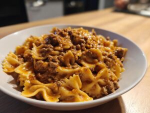 Close-up of creamy parmesan garlic beef bowtie pasta served in a white bowl on a wooden surface.