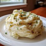 A generous serving of creamy roasted garlic mashed potatoes topped with melted butter and fresh parsley.