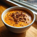 Close-up of a white bowl filled with creamy, orange rotel dip topped with seasoned ground meat.