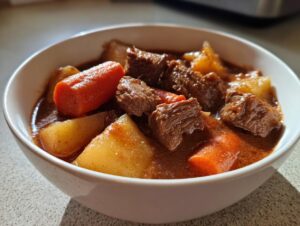 Close-up of tender beef chunks, carrots, and potatoes in a rich gravy, ready to eat crockpot beef stew.