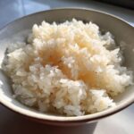Close-up of perfectly seasoned and fluffy sushi rice grains in a small white bowl.