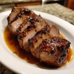 Close-up of perfectly cooked and sliced pork tenderloin recipe drizzled with a rich, dark glaze.