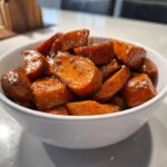 Close-up of rich, glossy southern candied yams served in a white bowl.