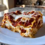 Close-up of a cheesy, layered slice of instant pot lasagna served on a white plate.