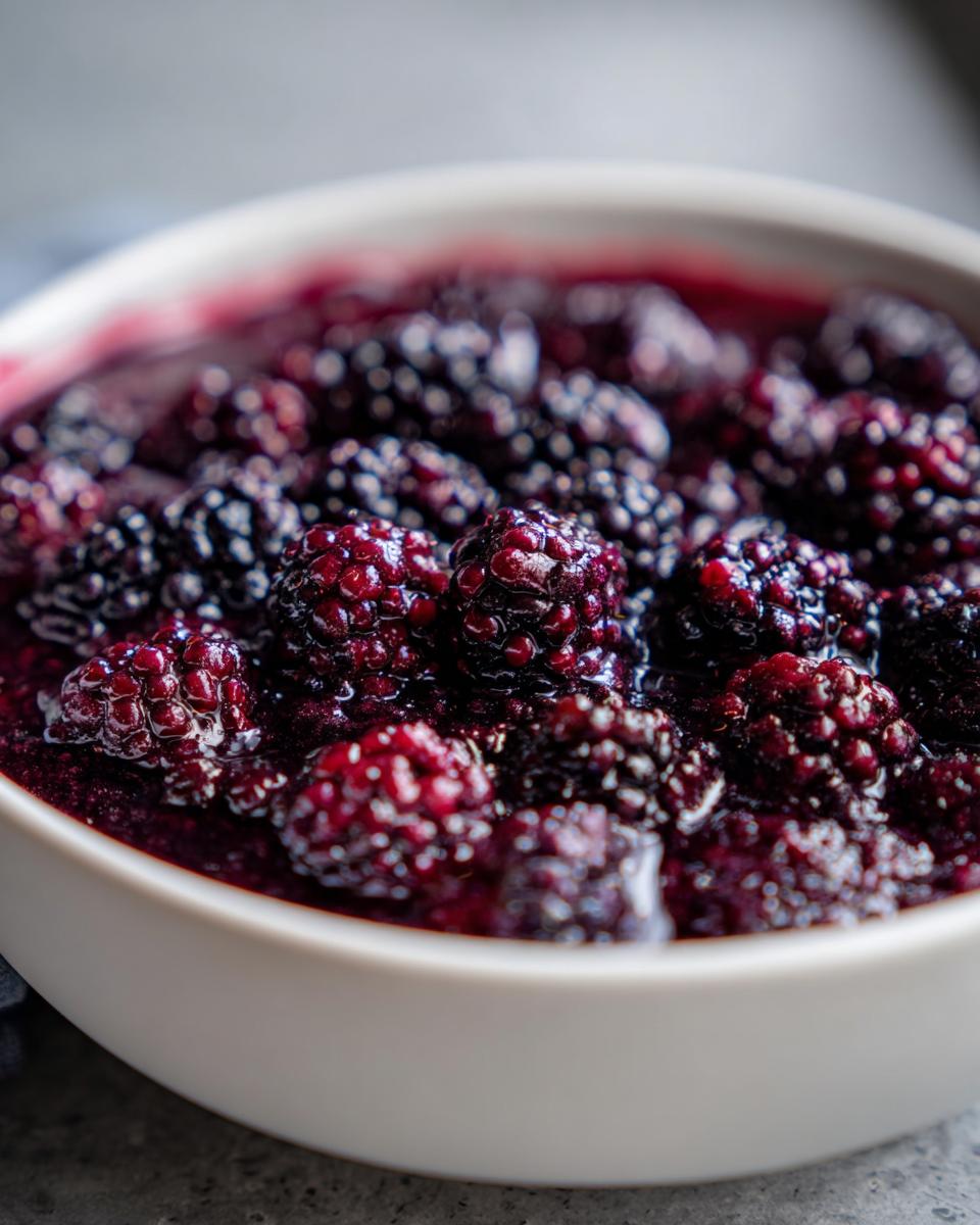 Close-up of plump, dark blackberries simmering in rich syrup, ready for Blackberry Dumplings.
